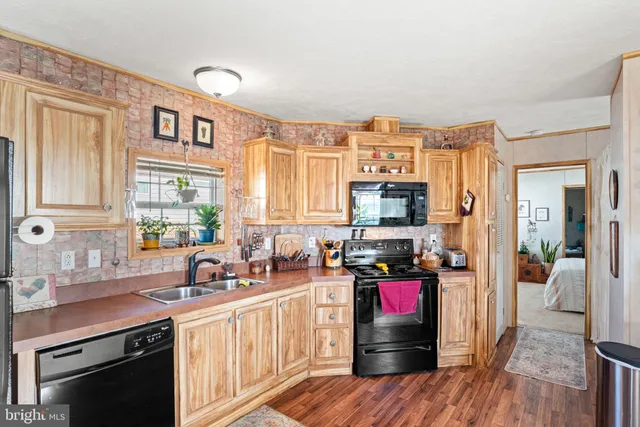 a kitchen with stainless steel appliances a stove top oven a sink dishwasher and wooden cabinets with wooden floor