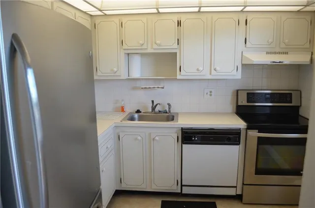 a kitchen with white cabinets and appliances