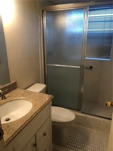 a bathroom with a granite countertop sink toilet and shower