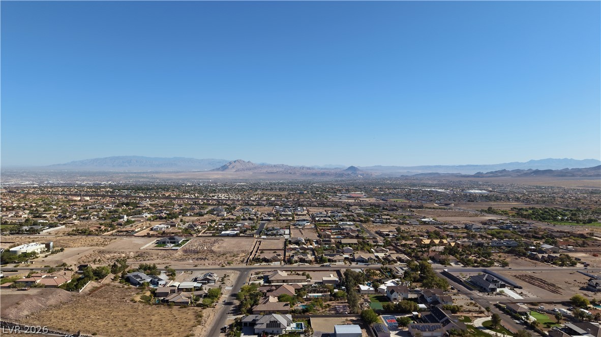 1243 Gloria Mountain Road Henderson, NV 89002 - Photo 9 of 12 A vast desert landscape unfolds with a community nestled amongst distant mountain ranges.