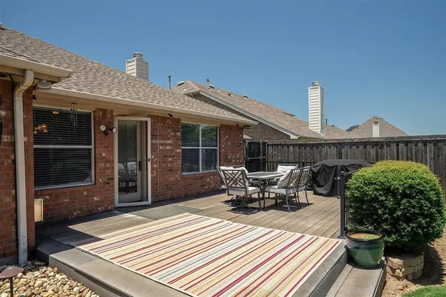 a view of a patio with table and chairs with wooden floor and fence