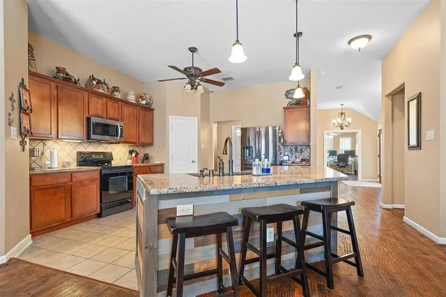 a kitchen with stainless steel appliances a table chairs refrigerator and microwave