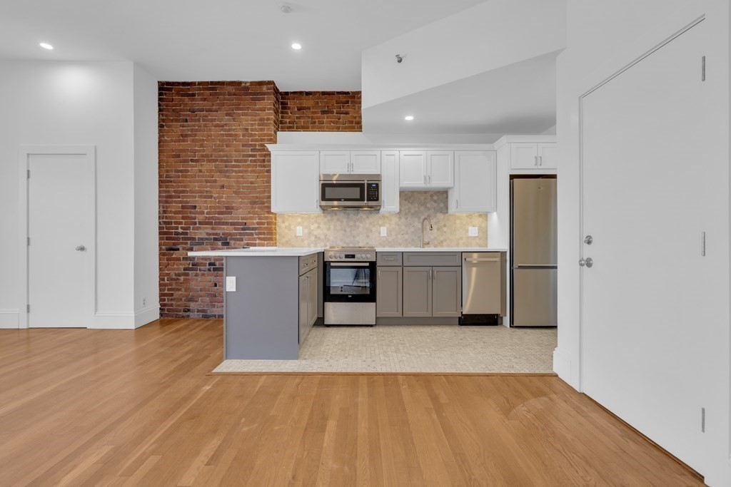 389 Beacon Street, Unit 7 Boston, MA 02116 - Photo 7 of 12 a large kitchen with stainless steel appliances granite countertop a stove a sink and a microwave