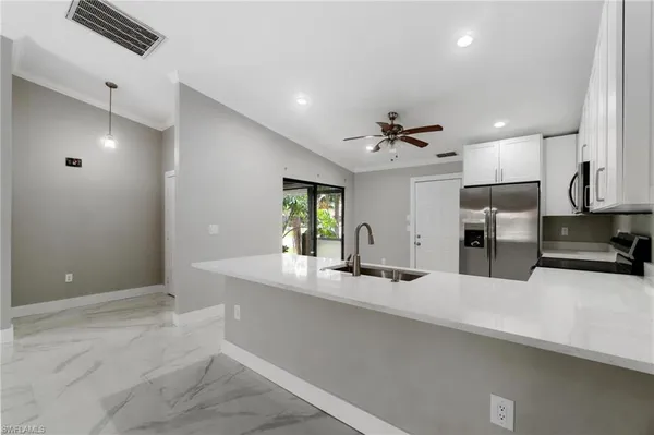 a view of a kitchen with a sink a kitchen island and stainless steel appliances