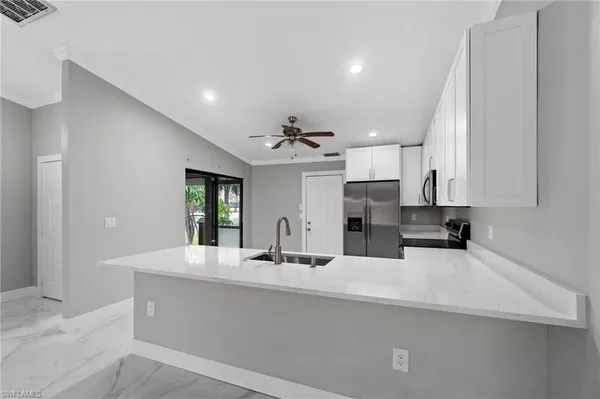 a large kitchen with stainless steel appliances a large counter top a sink a refrigerator and a granite counter tops