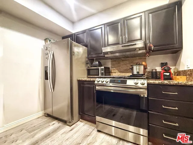 a metallic refrigerator freezer sitting inside of a kitchen
