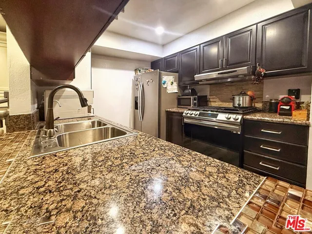 a kitchen with stainless steel appliances granite countertop a sink refrigerator stove and microwave