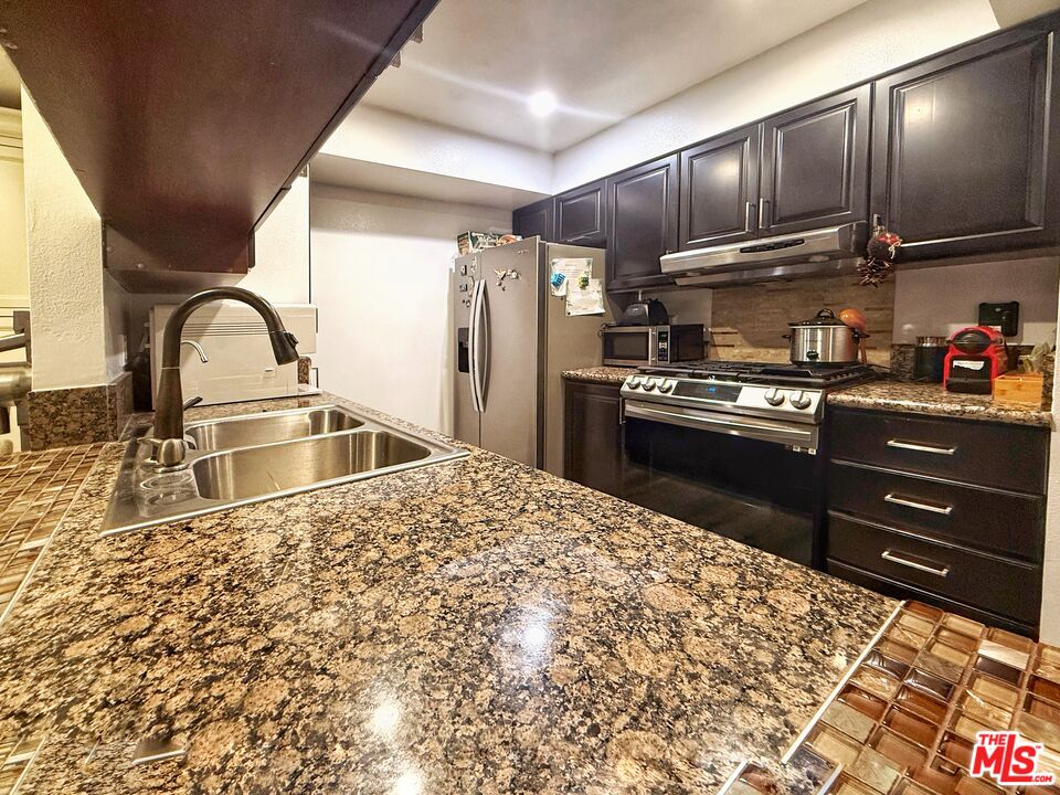 1118 Valencia Street, Unit 320 Los Angeles, CA 90015 - Photo 13 of 24 a kitchen with stainless steel appliances granite countertop a sink refrigerator stove and microwave