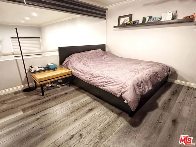 a bedroom with a bed and a potted plant on dresser