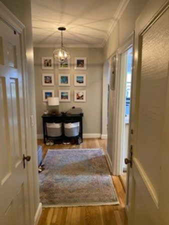 a view of a hallway with wooden floor and a cabinet