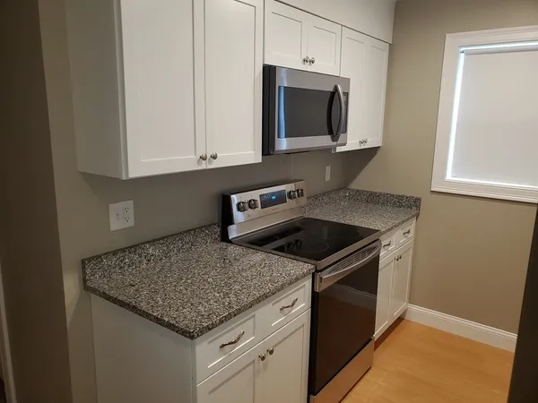 a kitchen with granite countertop a sink stove and microwave