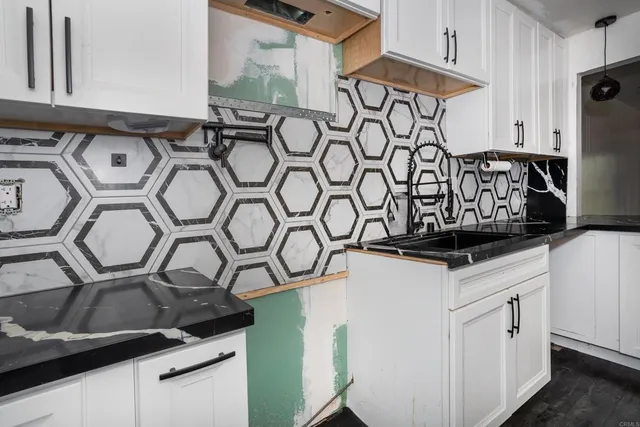 a kitchen with white cabinets and sink