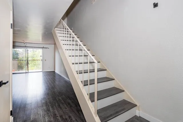 a view of staircase with wooden floor and white walls