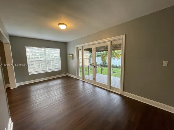 a view of an empty room with wooden floor and a window