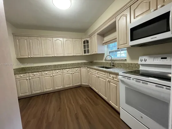 a kitchen with granite countertop white cabinets and white appliances