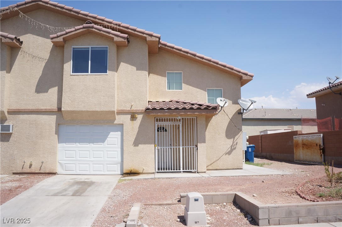 6148 Bluehill Avenue, Unit 2 Las Vegas, NV 89156 - Photo 1 of 13 Rear view of property featuring stucco siding, driveway, a tiled roof, and an attached garage