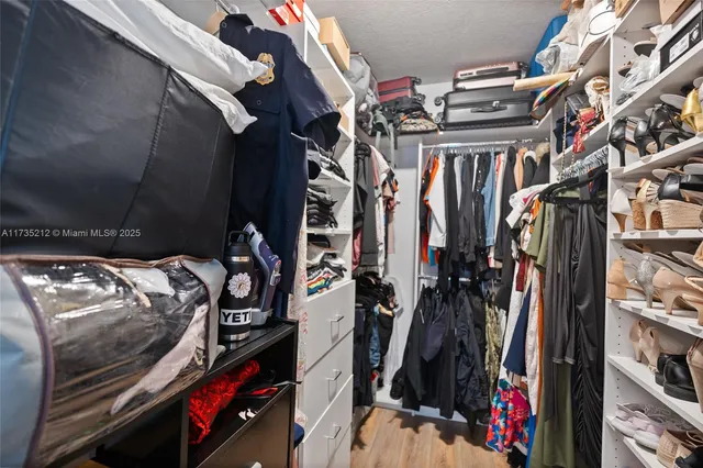 a view of walk in closet with clothes and shoes