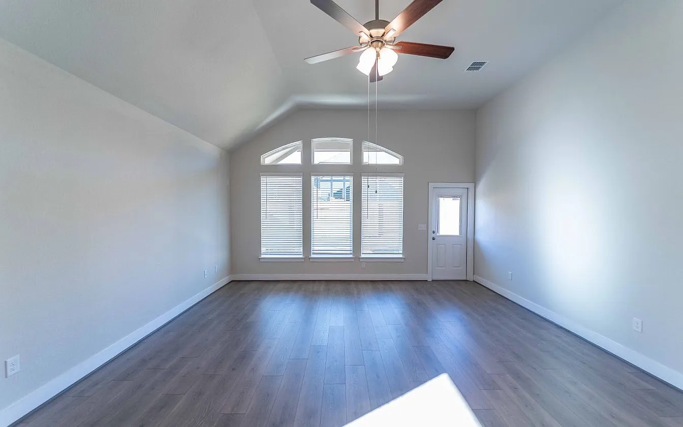 450 Durian Loop Buda, TX 78610 - Photo 4 of 17 A spacious room features vaulted ceilings, a large arched window, and a convenient exterior door.