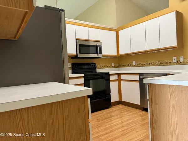 a kitchen with stainless steel appliances a microwave a stove and white cabinets