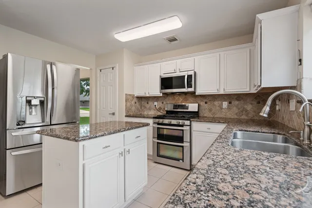 a kitchen with kitchen island granite countertop a stove sink and refrigerator