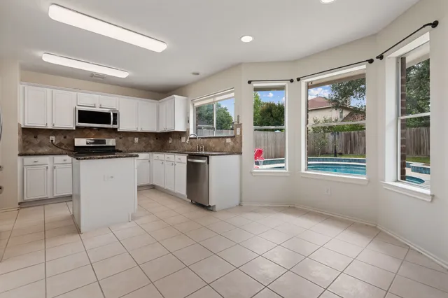 a kitchen with granite countertop a stove top oven a sink a counter top space cabinets and glass door