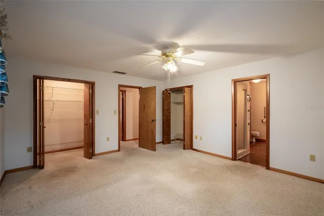 an empty room with closet and a ceiling fan