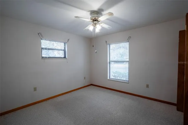 an empty room with a window and a ceiling fan