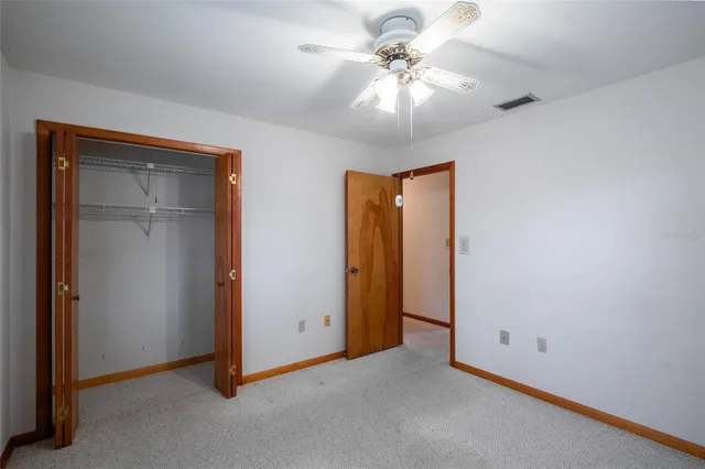 an empty room with a chandelier fan and a ceiling fan