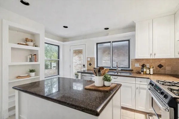 a kitchen with granite countertop a sink a stove and cabinets