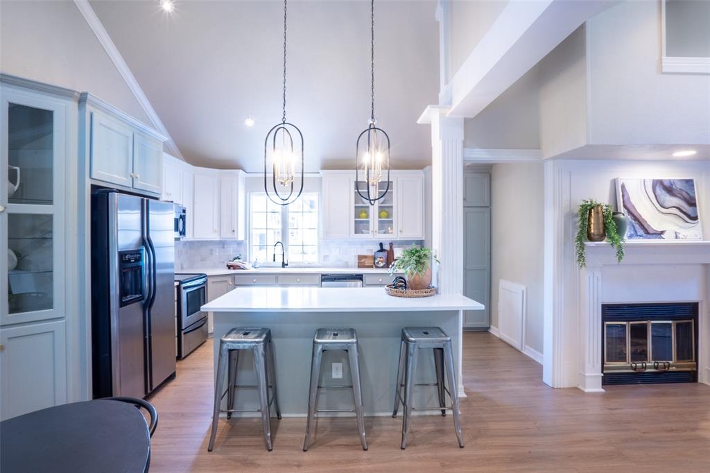 1415 Pecos Street Dallas, TX 75204 - Photo 7 of 25 a kitchen with stainless steel appliances a dining table chairs stove refrigerator and fireplace