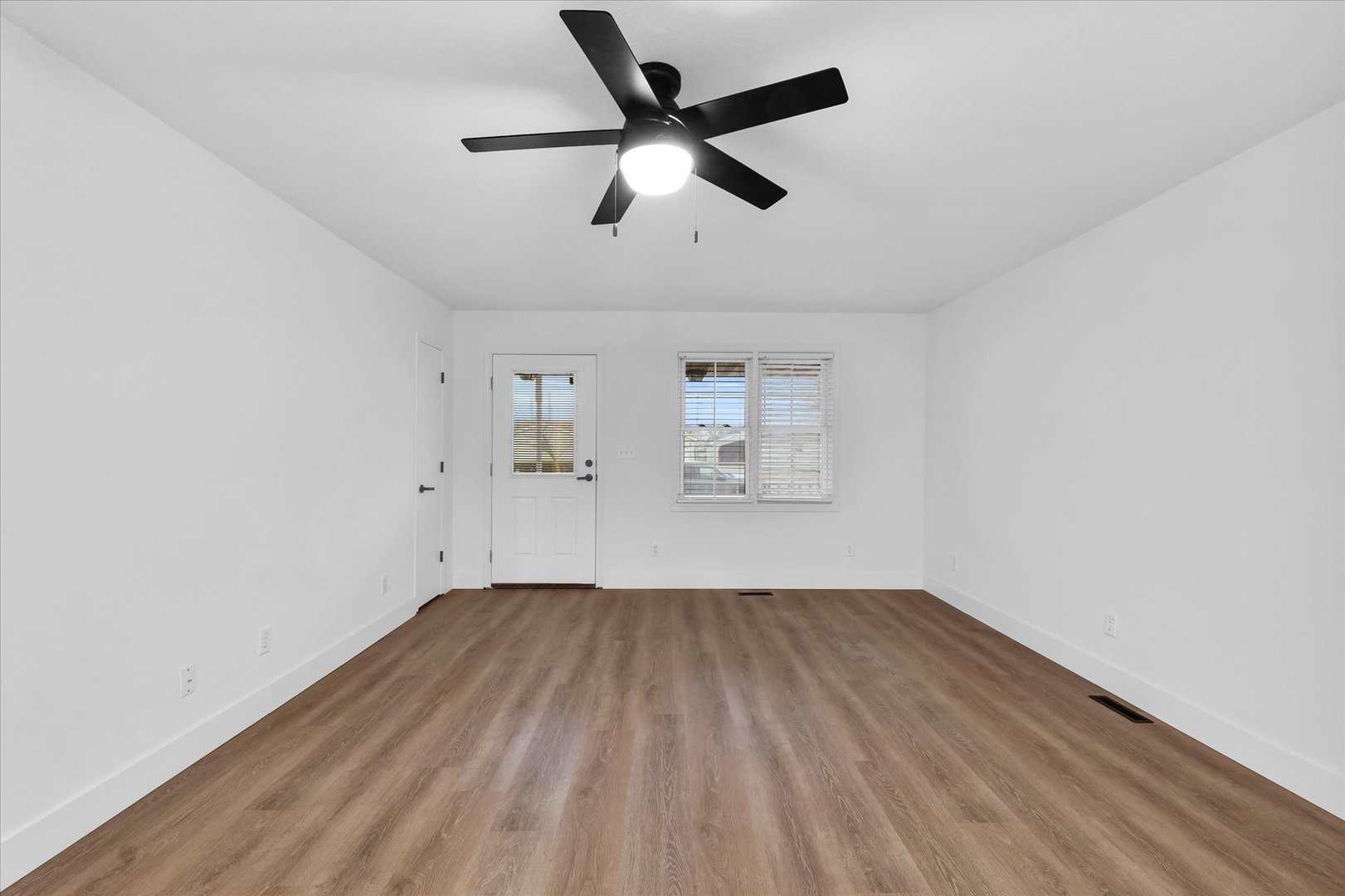 203 West Main Street Ogden, IL 61859 - Photo 6 of 27 an empty room with wooden floor ceiling fan and windows