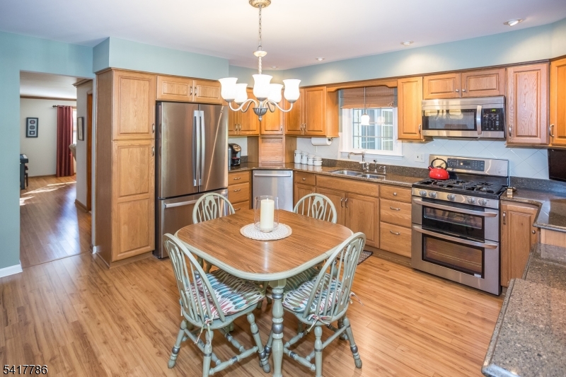10 Torlish Gate Raritan, NJ 08869 - Photo 7 of 40 a kitchen with stainless steel appliances granite countertop a stove a refrigerator a kitchen island a dining table and chairs with wooden floor