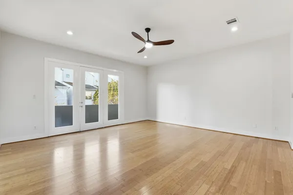 an empty room with wooden floor and windows
