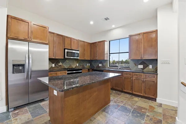 a kitchen with stainless steel appliances granite countertop a stove a sink and a refrigerator