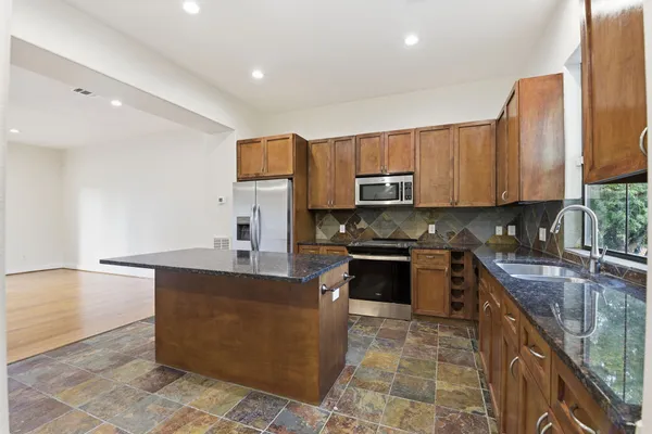 a large kitchen with stainless steel appliances granite countertop a sink stove and microwave
