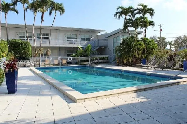 a view of a swimming pool with a yard and palm trees