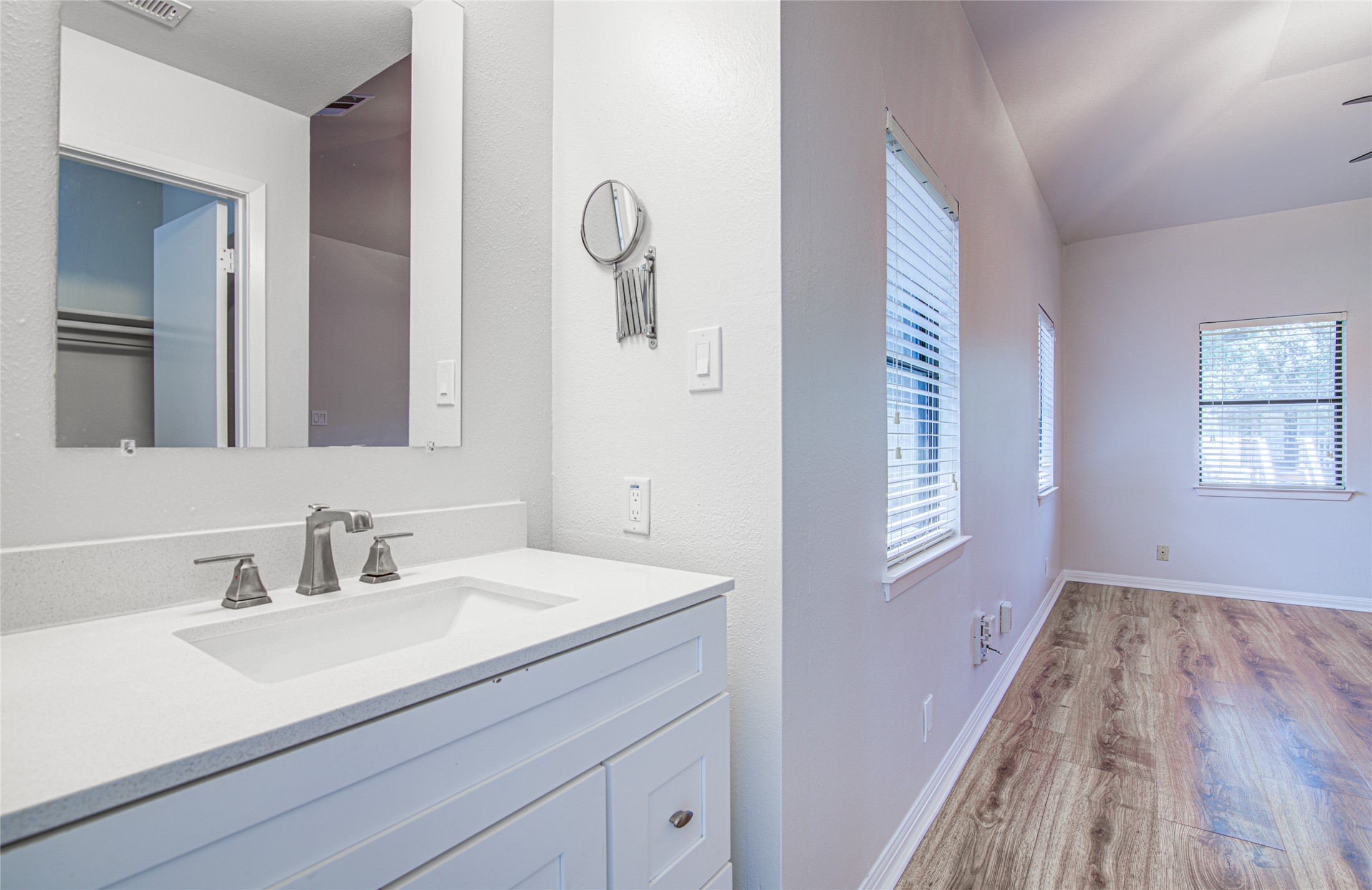 311 West Mary Street Austin, TX 78704 - Photo 11 of 35 A well-appointed vanity with a crisp white countertop complements the wood-look flooring and multiple windows, ensuring ample illumination.