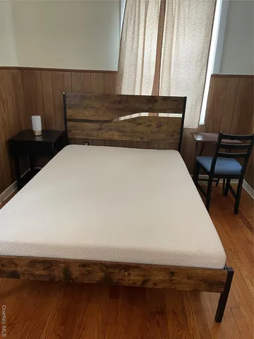 a bed sitting in a bedroom next to a window with wooden floor