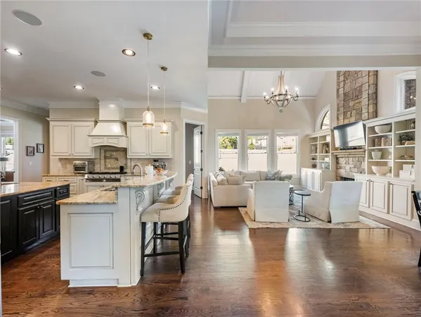 a kitchen with stainless steel appliances granite countertop a stove top oven a refrigerator a sink and dishwasher with wooden floor