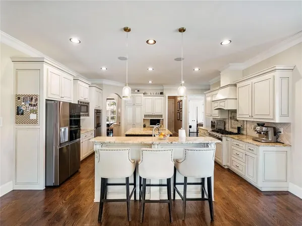 a kitchen with granite countertop a stove top oven a sink dishwasher a refrigerator and white cabinets with wooden floor