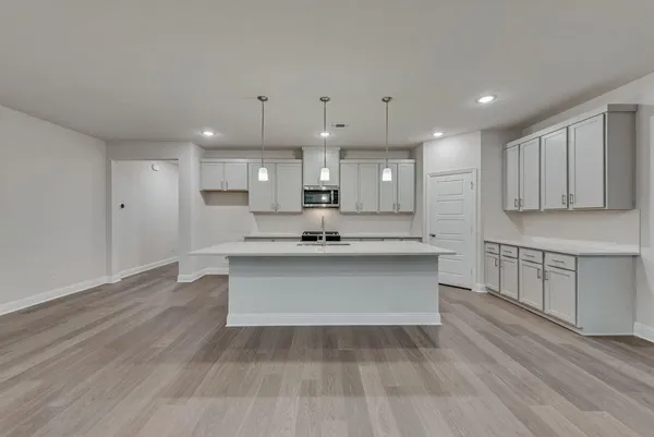 a large white kitchen with wooden floors stainless steel appliances and cabinets