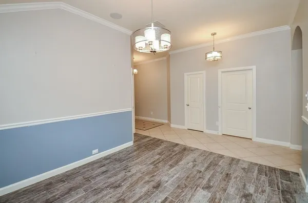 an empty room with wooden floor and chandelier