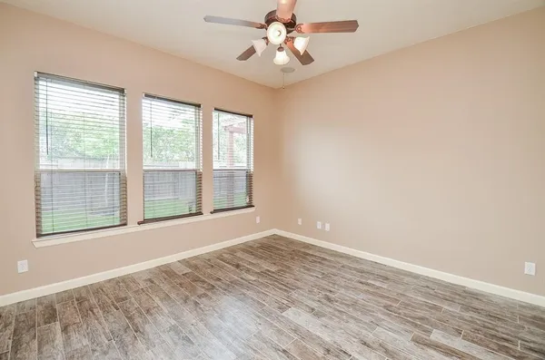 a view of an empty room with wooden floor and a window