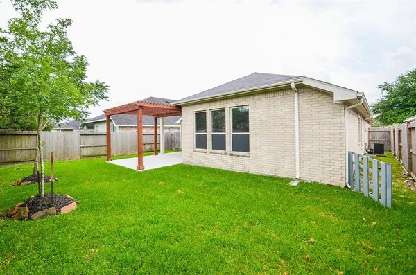 a backyard of a house with plants and large tree