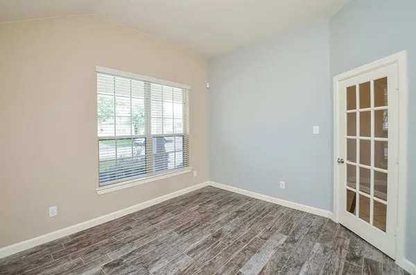 a view of an empty room with wooden floor and windows