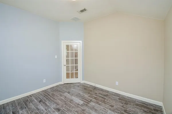 an empty room with wooden floor and windows