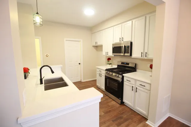 a kitchen with granite countertop a sink stainless steel appliances and white cabinets