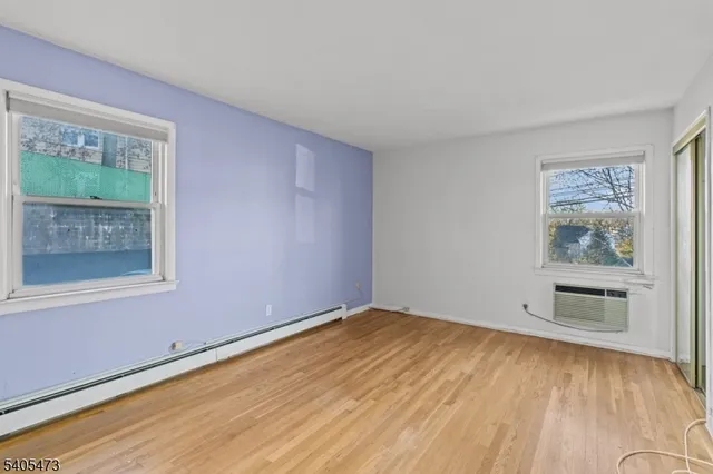 a view of empty room with window and wooden floor