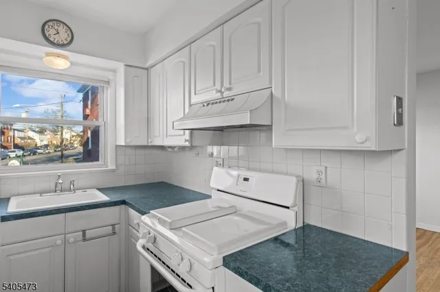 a kitchen with white cabinets and sink