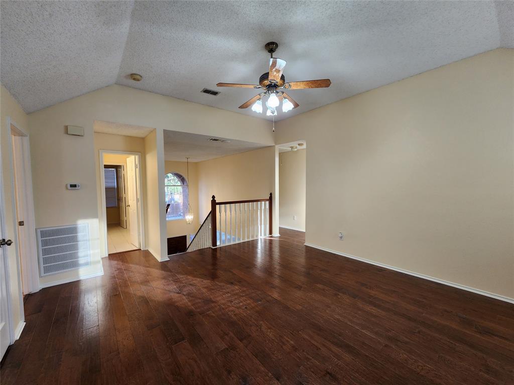 2413 Timber Ridge Lane Flower Mound, TX 75028 - Photo 27 of 32 Spacious room featuring vaulted ceilings, a ceiling fan with integrated lighting, wood-finish flooring, and light-toned wall paint